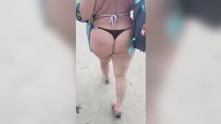 Blonde milf walking on beach in a thong